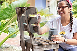 Young woman painting furniture in backyard of her home