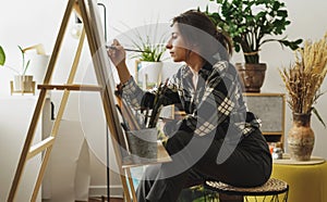 A young woman paints in her apartment with oil paints. Female student draws in art studio.Fine art study concept.