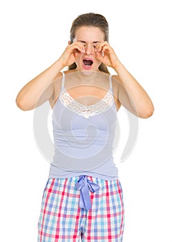 Young woman in pajamas rubbing eyes