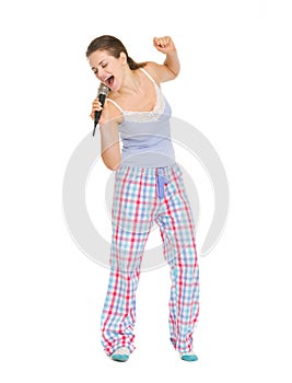 Young woman in pajamas singing in microphone