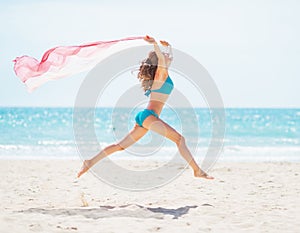 Young woman with parero jumping on beach