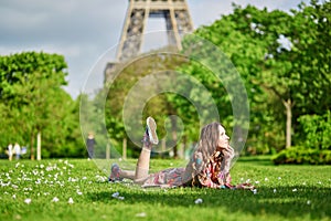 Young woman in Paris lying on the grass near the Eiffel tower on a nice spring or summer day