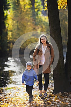 Young woman in the park in autumn with a child. mother with son.