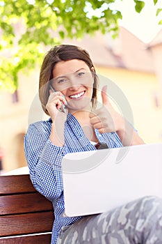 Mladá žena v parku s počítačom