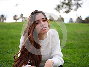 A young woman in the park looking at the camera seriously with a revengeful expression