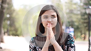 A young woman on a park, praying earnestly