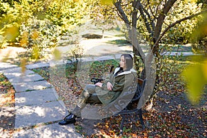 Young woman in park on sunny autumn day. Cheerful beautiful female in jacket with a hood outdoors on beautiful fall day