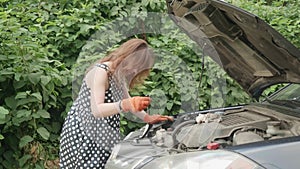 Young woman with parkinsonism stands infront of car and changes tools for car repairing. She takes out screwdriver.