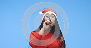 Young woman partying in santa hat with party horn