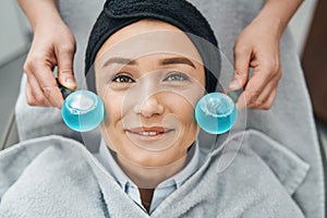 Young woman patient being massaged with facial ice globes