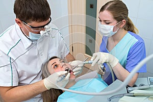 Young woman patient getting dental treatment at dental office, Dentist and assistant during teamwork.