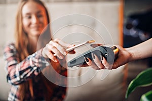 Young woman pay by mobile phone in cafe