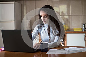 Young woman paying bills with debit card from home