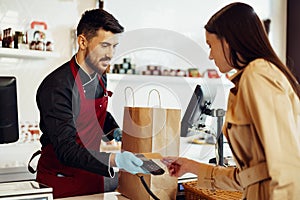 Young woman paying credit card for purchases in grocery store.