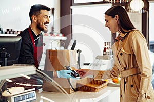 Young woman paying credit card for purchases in grocery store.