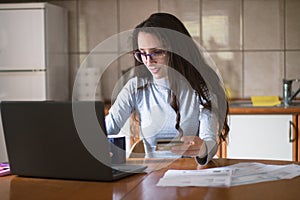 Young woman paying her bills online with credit card