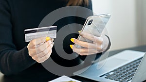 A young woman pays with a credit card online while making an online purchase on a laptop. Successful business people transact usin