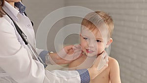 A young woman pediatrician examines a throat and lymph nodes a child.