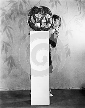 Young woman peeking from a behind of a Jack O' Lantern