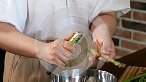 Young woman peeling asparagus in her kitchen