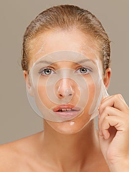 Young woman peeling off a facial mask