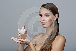 Young woman with perfect skin carries out a wash. Gray background