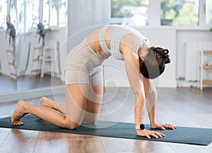 Young woman performing back stretching Marjaryasana asana