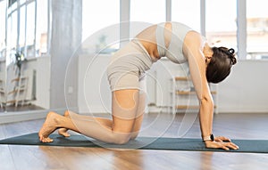 Young woman performing back stretching Marjaryasana asana