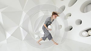 Young woman performing contemporary dance moves in white studio with ball