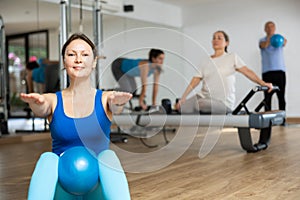 Young woman performing sit-up with bender ball in fitness studio