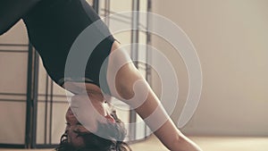 A young woman performing yoga-asanas in the hall.