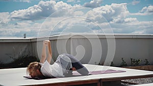 Young woman performs advanced asanas of Hatha yoga is lying on yoga mat