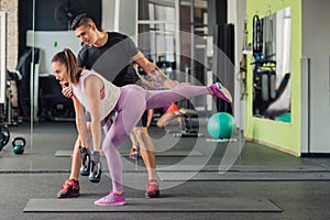Young woman with personal trainer in the gym