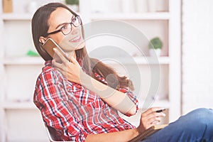 Young woman on phone taking notes