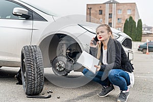 Young woman phoning near car without wheel