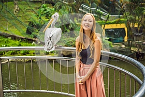 A young woman is photographed with a pelican. Great white pelican also known as the eastern white pelican, rosy or white