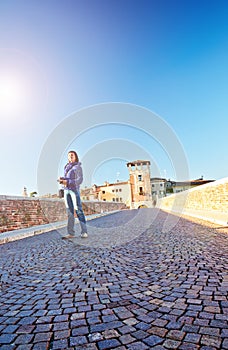 Young woman photographer beams morning sun bridge Ponto Pietra castel Vecchio river Adige Italy Verona