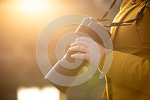 Young woman photographer with professional camer in hand during sunset