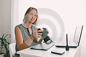 A young woman photographer sitting at his Desk and working with a camera. Copy space