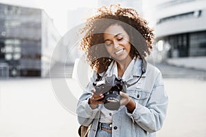 Young woman photographer takes photographs with dslr camera in a city.