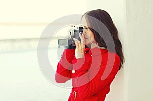 Young woman photographer takes picture on vintage camera in winter city