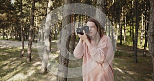 Young woman photographer takes pictures of the forest using digital camera
