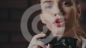 Young woman photographer using photo camera for take picture in studio