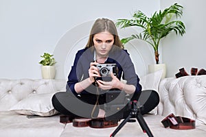 Young woman photographer with vintage camera recording video on smartphone
