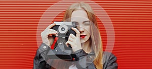 Young woman photographer with vintage film camera on a red background