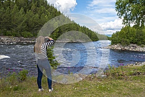 Young woman is photographing the landscape in the border of Fugga river in Hedmark county of Norway photo