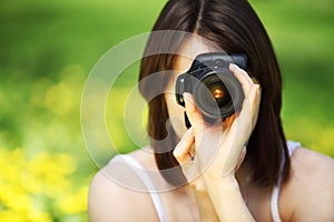 Young woman photographing in summer park