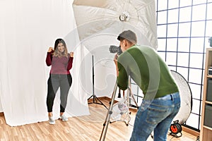 Young woman at photography studio very happy and excited doing winner gesture with arms raised, smiling and screaming for success