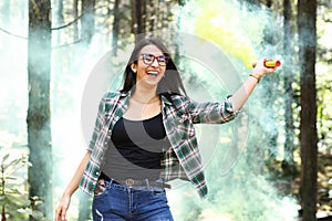 Young woman in a photoshoot raising her hand holding a smoke bomb yellow in the forest smiling at Costa Rica