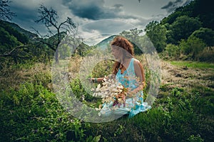 Young woman pick herbs and flowers on clean wild mountain meadow photo